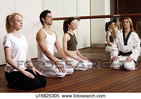 Stock Photography - Participants in a fitness class meditating. Fotosearch