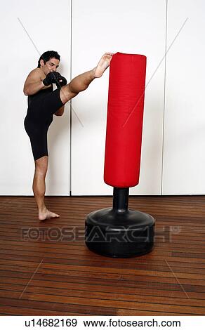 Stock Photo - Young man kicking a punching bag. Fotosearch