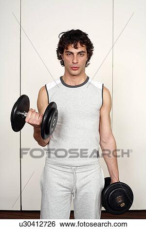 Stock Photograph - Young man lifting weights. Fotosearch