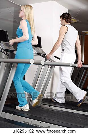 Young woman and man on treadmill View Large Photo Image Stock Image - Young woman and man on treadmill. Fotosearch