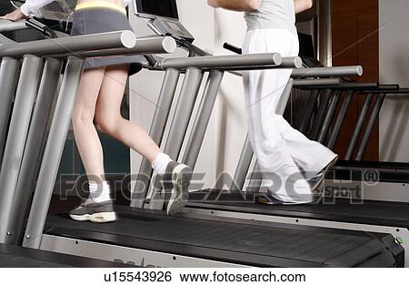 Young woman and man on treadmill, waste down View Large Photo Image Stock Photograph - Young woman and man on treadmill, waste down. Fotosearch