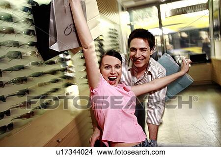 Happy couple posing with shopping bags in a sunglasses store View Large Photo Image Picture - Happy couple posing with shopping bags in a sunglasses store. Fotosearch