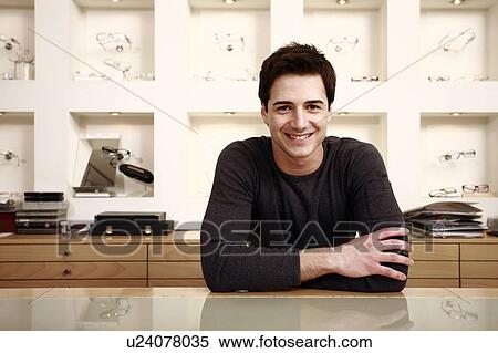 Stock Photography - Man posing at counter in eyeglass store. Fotosearch