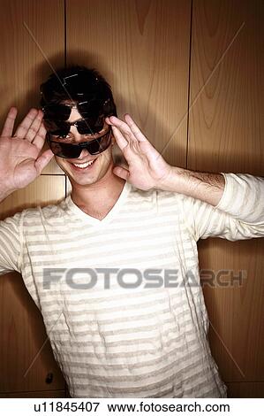 Stock Photo - Man trying on several sunglasses in store. Fotosearch