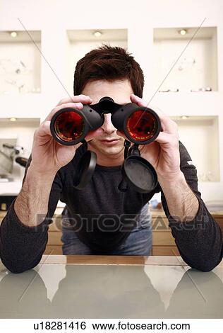 Stock Photograph - Man with binoculars in eyeglass store. Fotosearch
