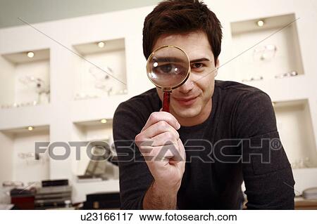 Stock Photo - Man with magnifying glass on eye. Fotosearch