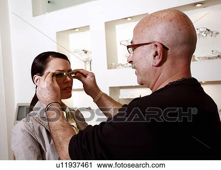 Stock Image - Woman having glasses fitted by optometrist. Fotosearch