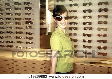 Stock Image - Woman shopping in sunglasses store. Fotosearch