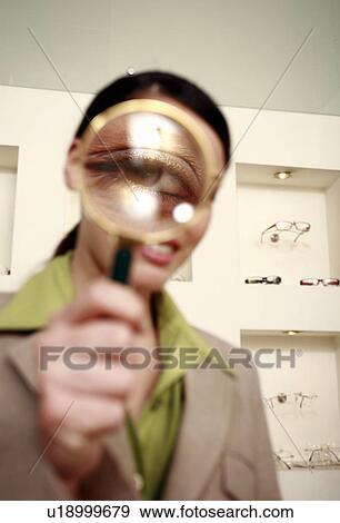 Stock Photo - Woman with magnifying glass on eye. Fotosearch