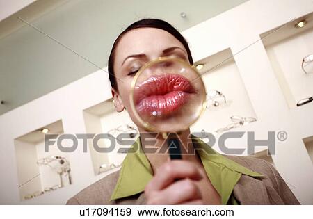 Stock Photo - Woman with magnifying glass on mouth. Fotosearch