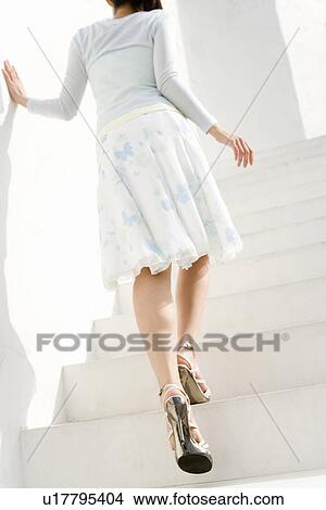 Picture - A woman walking up the stairs, rear view, low angle view. Fotosearch