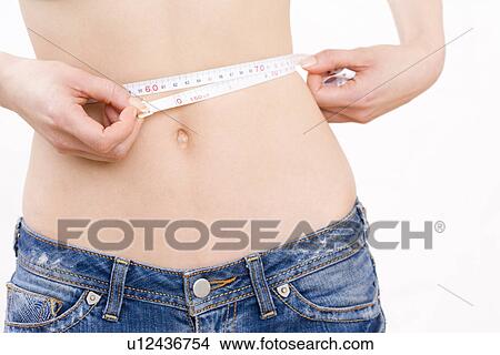 Picture - Mid section of woman measuring her waist . Fotosearch