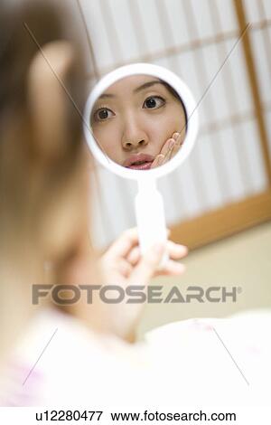 Stock Photo - Woman in Yukata holding a hand mirror, reflection of the mirror, rear view, Japan. Fotosearch