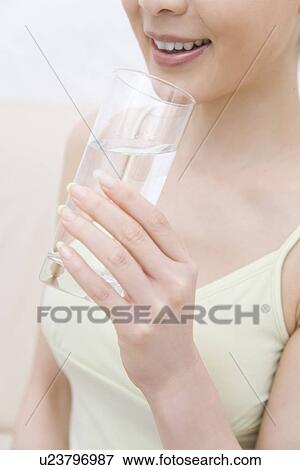 Young woman holding a cup of water, front view View Large Photo Image Stock Photo - Young woman holding a cup of water, front view. Fotosearch