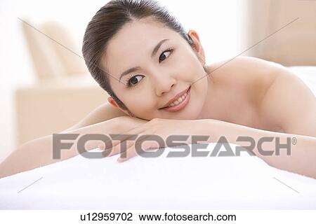 Stock Image - Young woman, lying on front, front view. Fotosearch