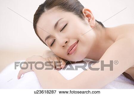 Stock Photo - Young woman, lying on front, front view. Fotosearch
