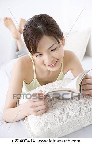 Young woman reading a book, lying on front, high angle view View Large Photo Image Picture - Young woman reading a book, lying on front, high angle view. Fotosearch