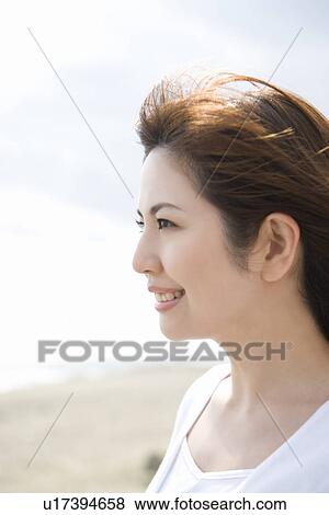 Stock Photo - Young woman, smiling, side view. Fotosearch