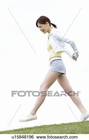 Young Woman walking on lawn, low angle view View Large Photo Image Stock Photograph - Young Woman walking on lawn, low angle view. Fotosearch