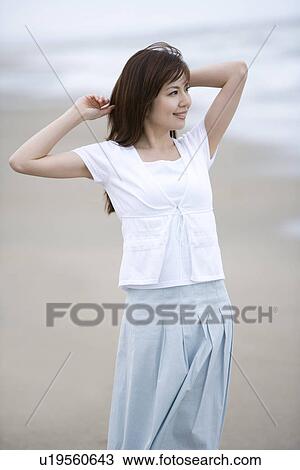 Stock Image - Young woman walking on the beach, front view . Fotosearch