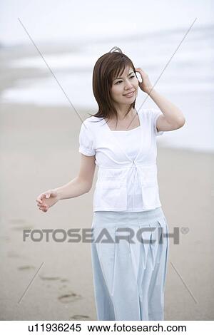 Stock Photography - Young woman walking on the beach, front view . Fotosearch