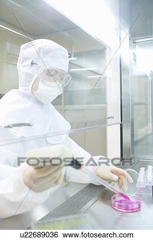 Stock Photograph - Female scientist dropping liquids into a petri dish, side view. Fotosearch