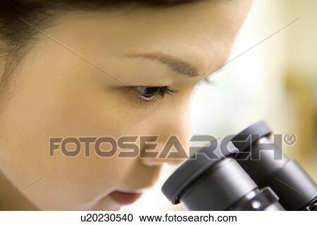 Female scientist looking through a microscope, side view, close up View Large Photo Image Stock Image - Female scientist looking through a microscope, side view, close up. Fotosearch