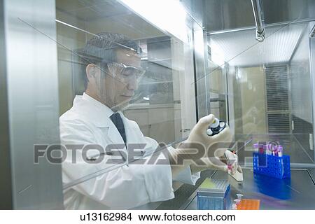 Male scientist dropping liquids into a micro test tube, side view View Large Photo Image Picture - Male scientist dropping liquids into a micro test tube, side view. Fotosearch