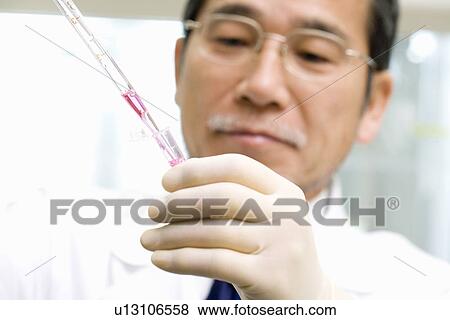 Male scientist dropping liquids into a test tube with pipette, front view View Large Photo Image Stock Photo - Male scientist dropping liquids into a test tube with pipette, front view. Fotosearch