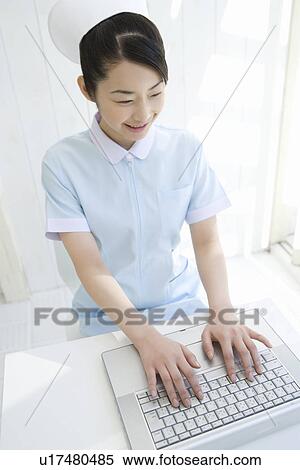 Stock Photography - Nurse using laptop, smiling, high angle view. Fotosearch