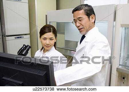 Two scientists talking and looking at a computer monitor, front view, side view View Large Photo Image Stock Photo - Two scientists talking and looking at a computer monitor, front view, side view. Fotosearch