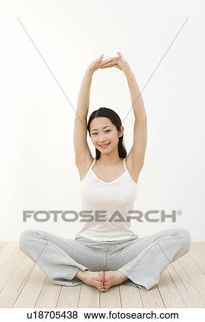 Portrait of a woman sitting cross-legged and stretching arms, front view, white background View Large Photo Image Stock Photo - Portrait of a woman sitting cross-legged and stretching arms, front view, white background. Fotosearch