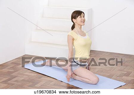Young woman doing yoga exercise, stretching, high angle view View Large Photo Image Picture - Young woman doing yoga exercise, stretching, high angle view . Fotosearch