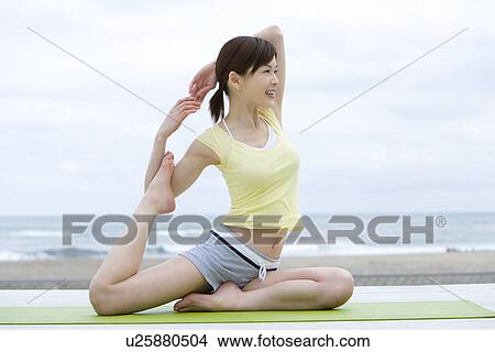 Young woman doing yoga exercise, stretching, side view View Large Photo Image Picture - Young woman doing yoga exercise, stretching, side view . Fotosearch