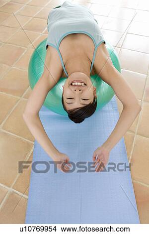 Picture - Young woman reclining on an exercise ball, stretching, high angle view. Fotosearch
