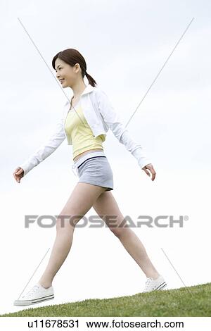 Young Woman walking on lawn, low angle view, side view View Large Photo Image Stock Image - Young Woman walking on lawn, low angle view, side view. Fotosearch