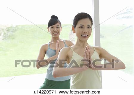 Stock Image - Young women doing yoga exercise, front view . Fotosearch