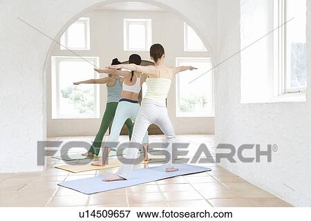 Stock Photo - Young women doing yoga exercise, stretching, rear view . Fotosearch