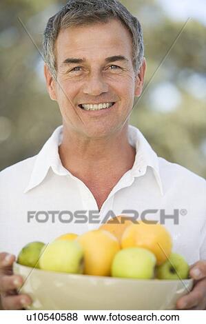 Stock Photo - A man holding a bowl of fruit. Fotosearch