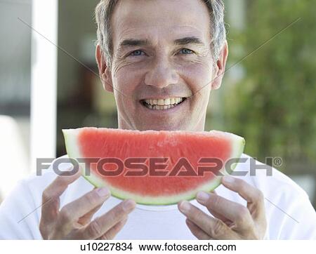 A man holding a slice of watermelon View Large Photo Image Picture - A man holding a slice of watermelon. Fotosearch