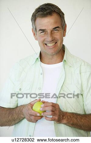 Stock Image - A man holding an apple. Fotosearch