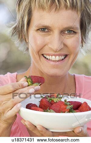 A woman eating a bowl of strawberries View Large Photo Image Stock Image - A woman eating a bowl of strawberries. Fotosearch