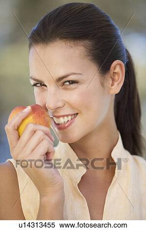 Stock Photography - A woman eating a peach. Fotosearch