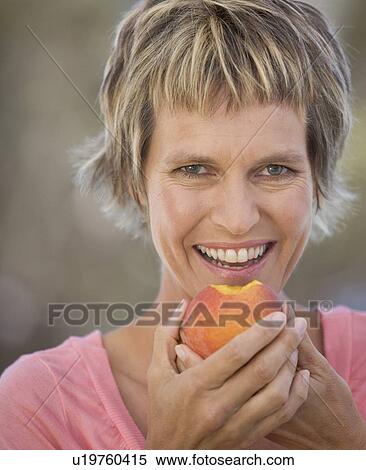 A woman eating a peach View Large Photo Image Stock Photography - A woman eating a peach. Fotosearch