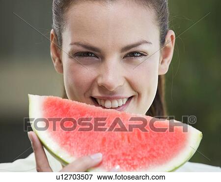 A woman eating a slice of watermelon View Large Photo Image Stock Photo - A woman eating a slice of watermelon. Fotosearch