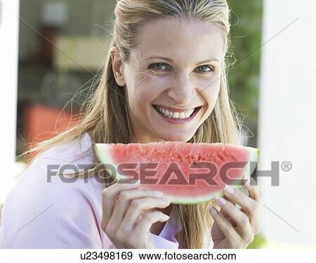 A woman eating a slice of watermelon View Large Photo Image Stock Photo - A woman eating a slice of watermelon. Fotosearch
