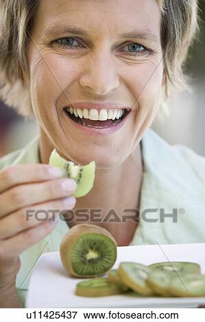 A woman eating kiwi fruit View Large Photo Image Stock Photo - A woman eating kiwi fruit. Fotosearch