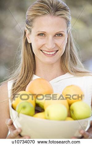 A woman holding a bowl of fruit View Large Photo Image Stock Image - A woman holding a bowl of fruit. Fotosearch