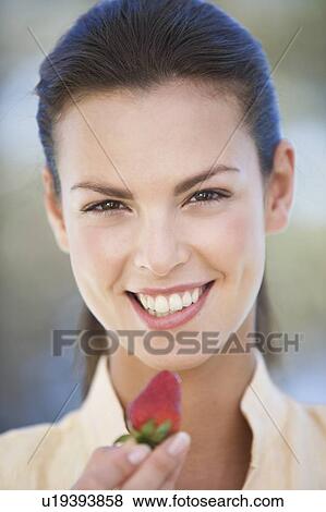 Stock Photo - A woman holding a strawberry. Fotosearch