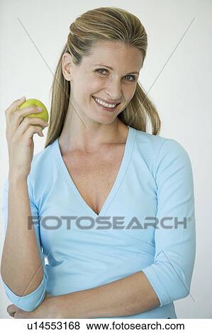 A woman holding an apple View Large Photo Image Stock Photo - A woman holding an apple. Fotosearch